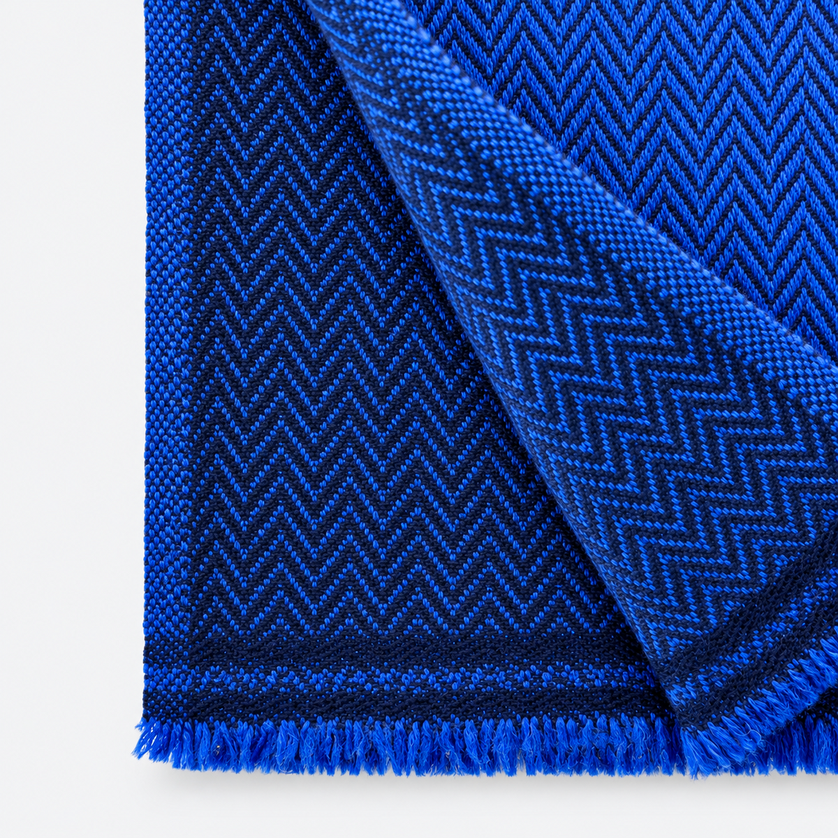 Close-up of cobalt blue and dark herringbone weave with fringe