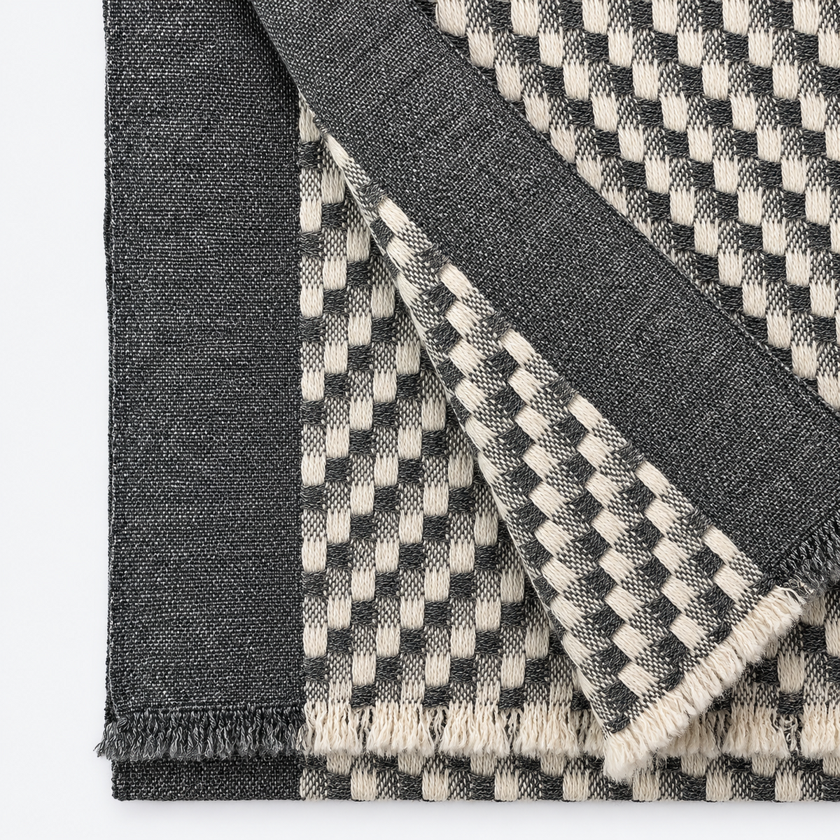 Close-up of charcoal and cream checkered cashmere weave and fringe