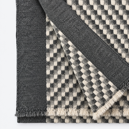 Close-up of charcoal and cream checkered cashmere weave and fringe