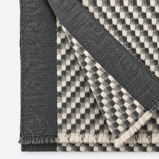 Close-up of charcoal and cream checkered cashmere weave and fringe