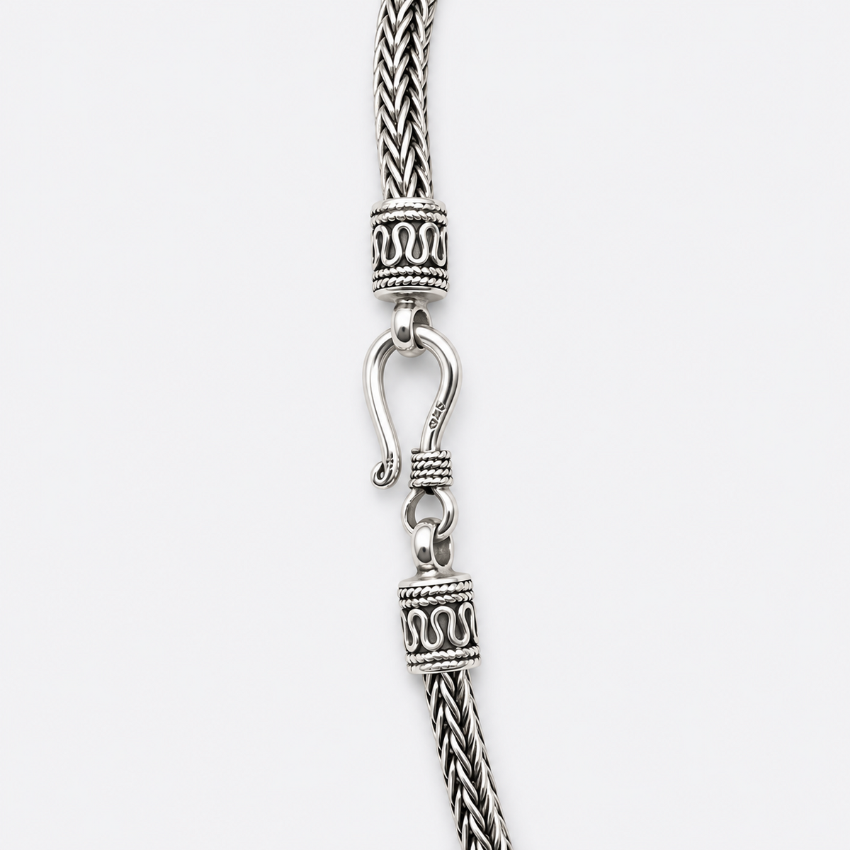 Decorative end caps and hook clasp detail on silver woven necklace