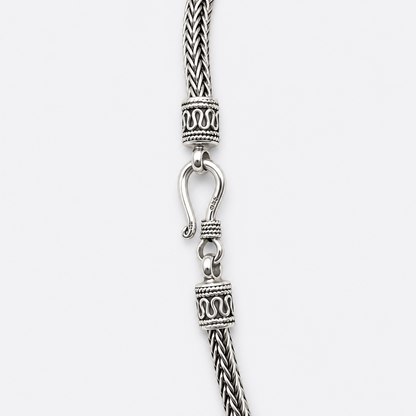 Decorative end caps and hook clasp detail on silver woven necklace